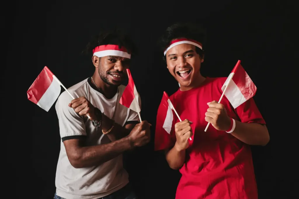 Pemuda-pemudi Indonesia merayakan kemerdekaan dengan penuh semangat sambil membawa bendera merah putih