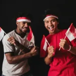 Pemuda-pemudi Indonesia merayakan kemerdekaan dengan penuh semangat sambil membawa bendera merah putih