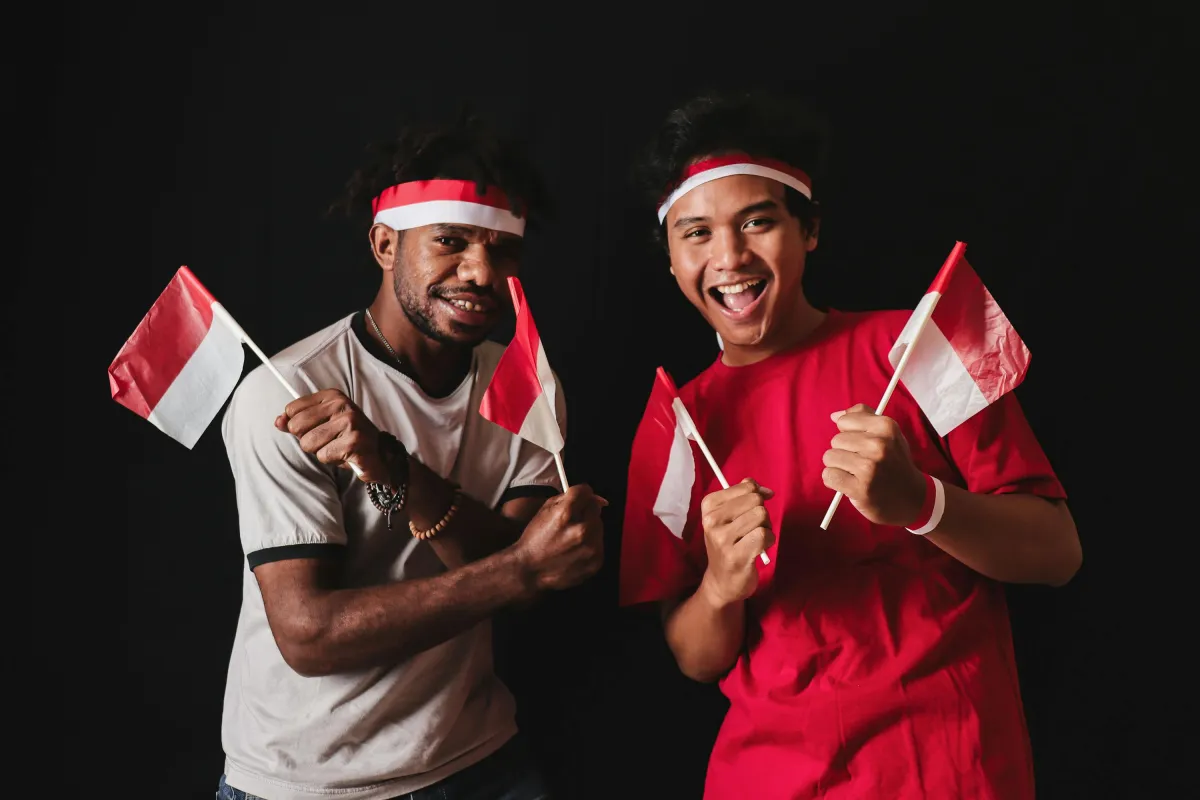 Pemuda-pemudi Indonesia merayakan kemerdekaan dengan penuh semangat sambil membawa bendera merah putih